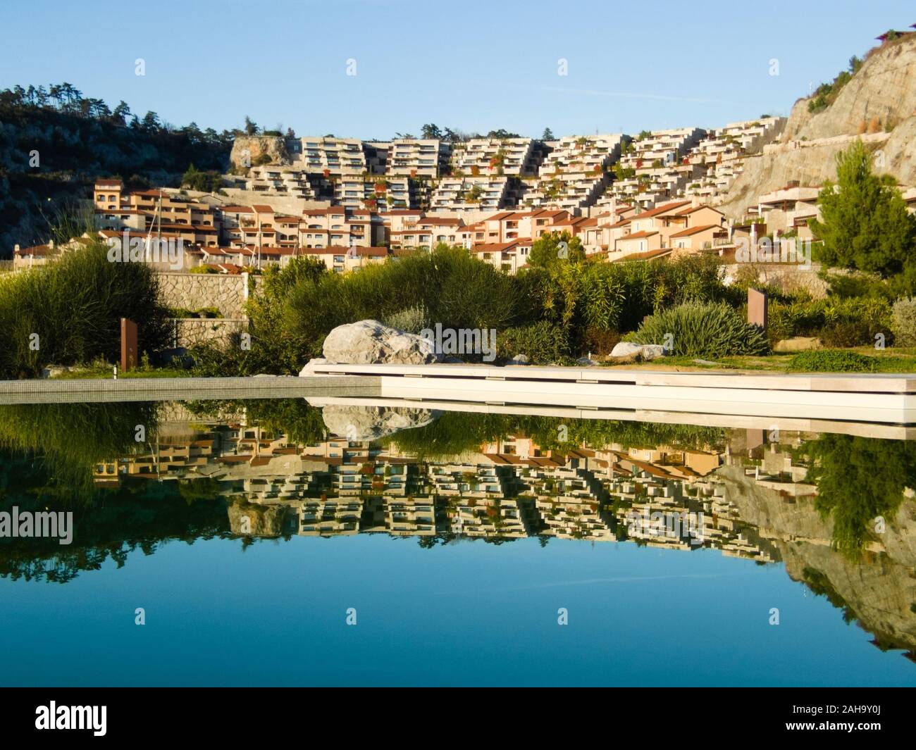 Reflets dans l'eau d'une piscine extérieure des maisons dans le village de vacances de Portopiccolo au cours d'une journée ensoleillée. L'exemple de Banque D'Images