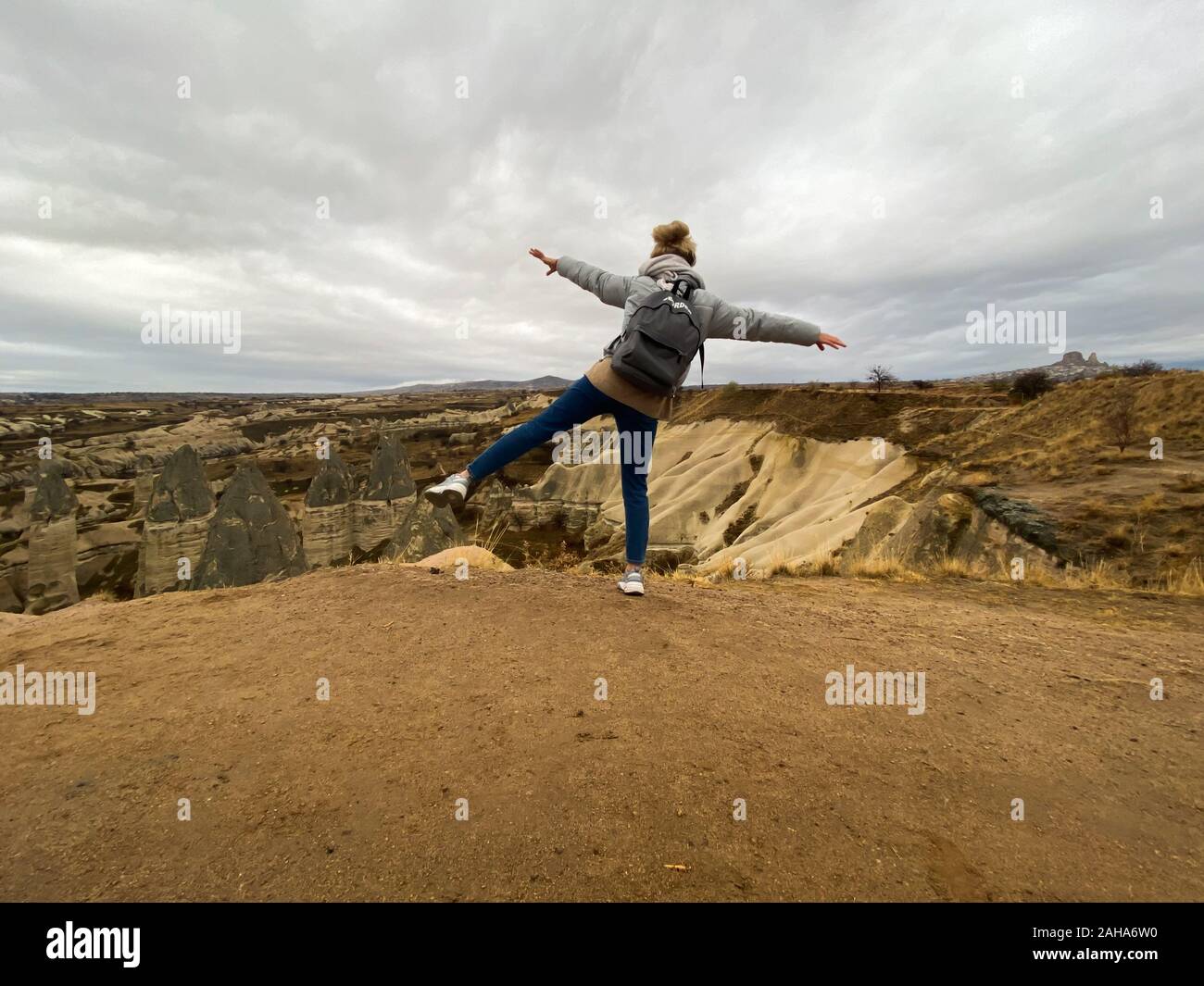 La jeune fille se tient sur une jambe en haut d'une montagne et étendit ses bras. Symbole de liberté et de réussite. Vue sur la vallée. La Cappadoce. La Turquie. Une populaire Banque D'Images