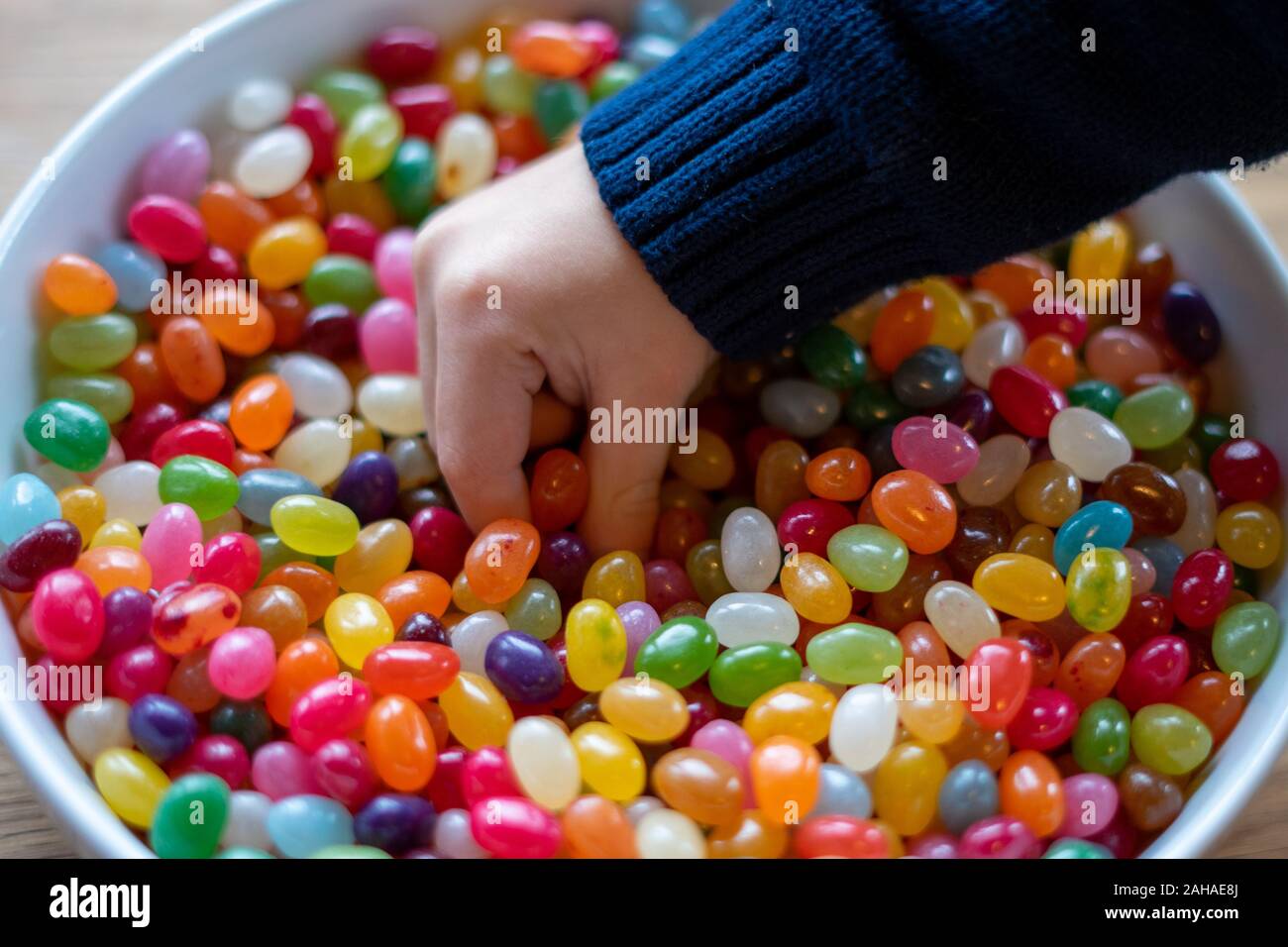 La main d'un enfant qui plongent dans un bol de bonbons Banque D'Images