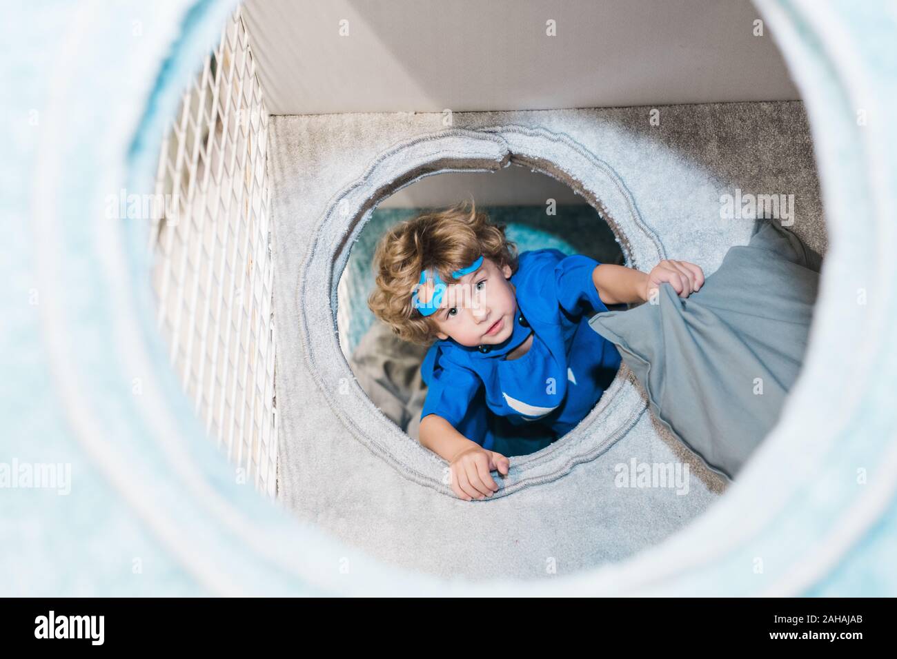 Mignon petit garçon blond en costume de superman bleu jouant dans des chambre Banque D'Images