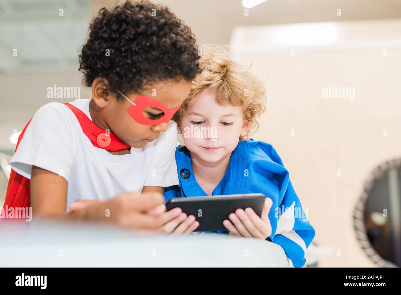 Deux petits garçons en costumes sympathique interculturel de superman regardant la vidéo Banque D'Images
