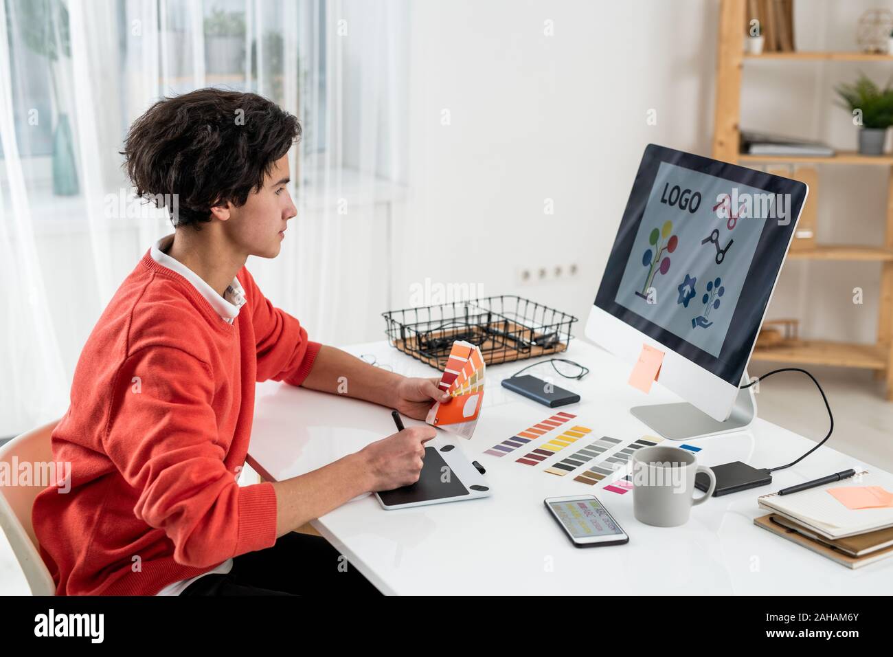 Jeune designer avec une palette de couleurs à la recherche à l'écran de l'ordinateur sur le logo Banque D'Images