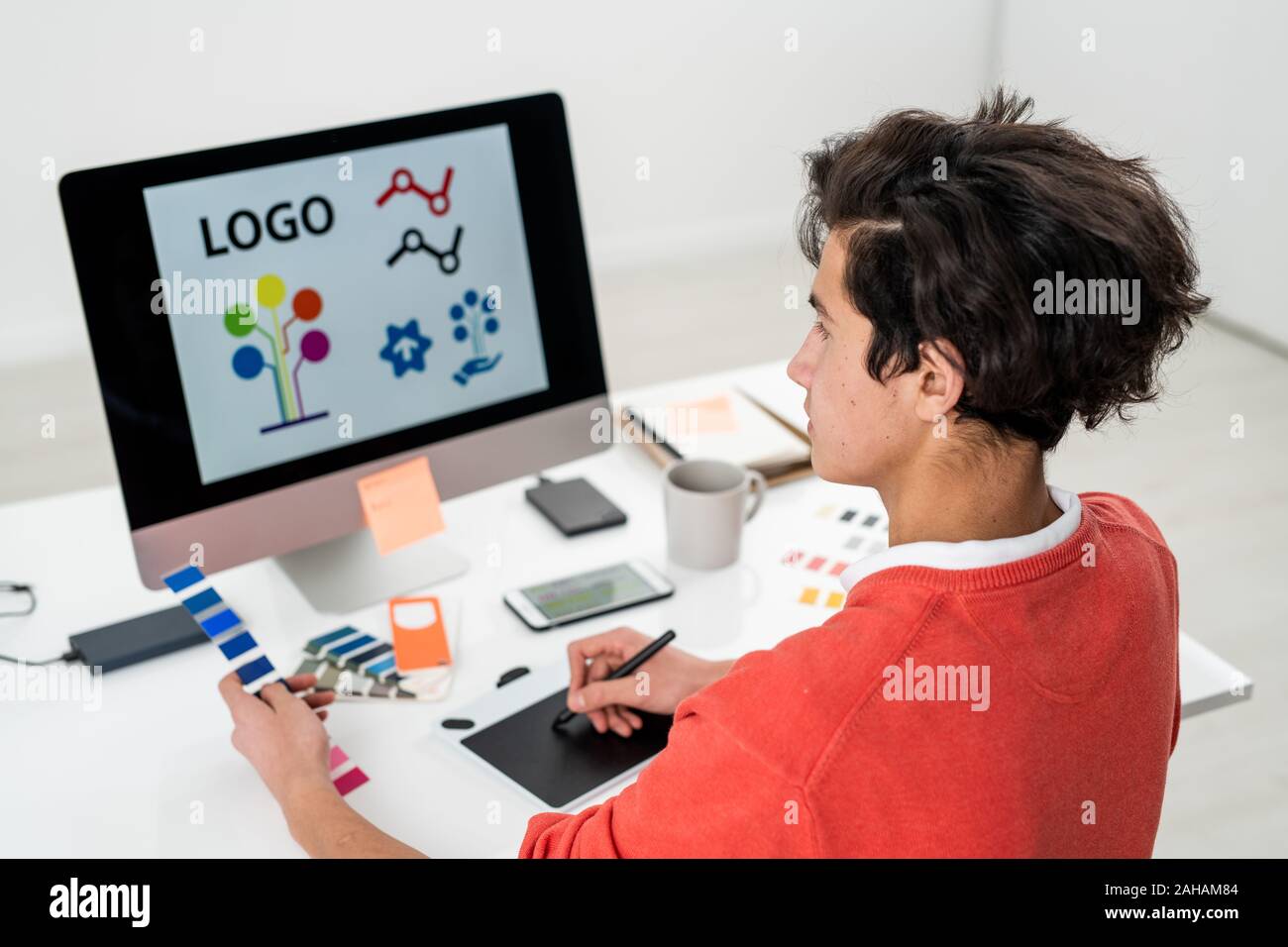 Jeune homme avec la palette de la création de logo pour site internet en face de l'ordinateur Banque D'Images