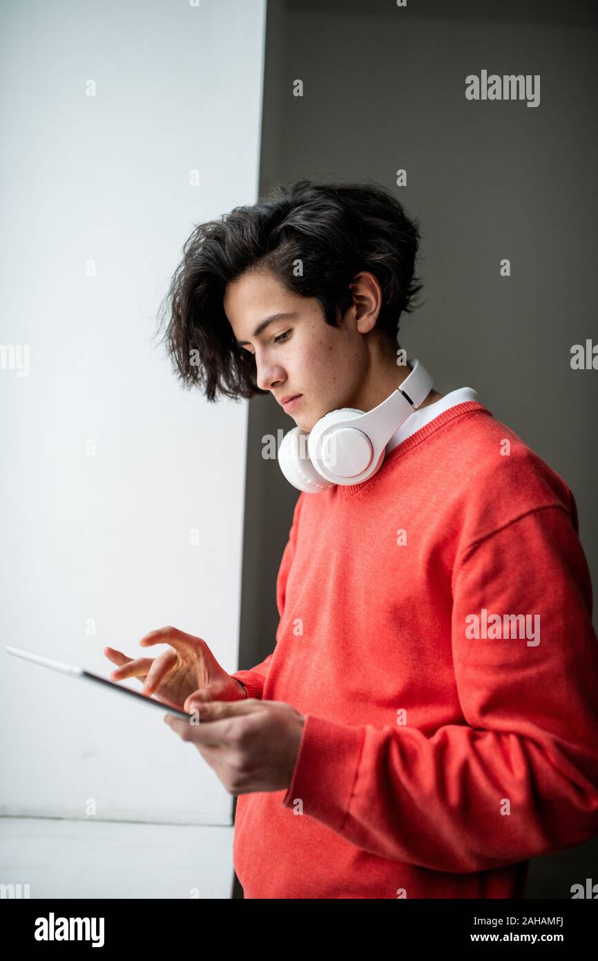 Casual guy avec un casque à l'aide de tablet en surfant sur le net par fenêtre Banque D'Images