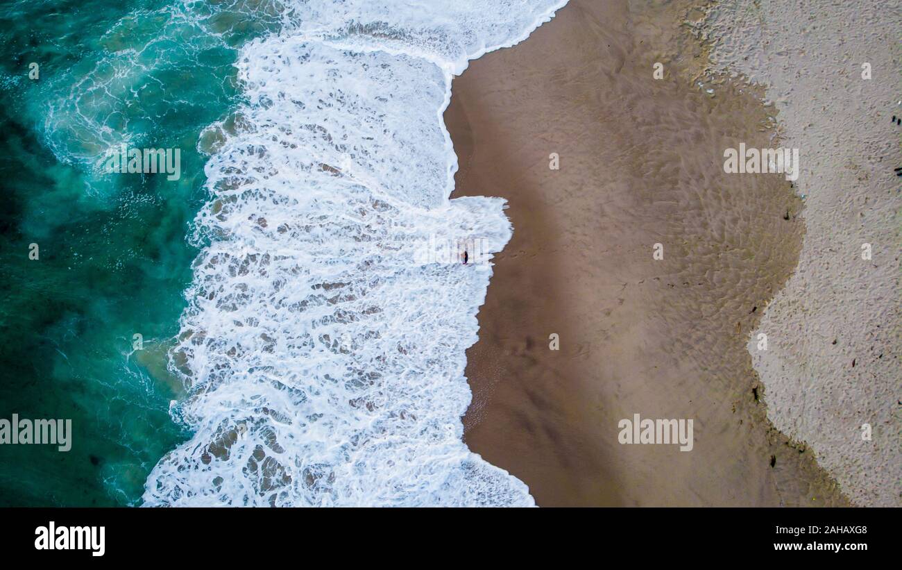 Vue aérienne d'un homme debout, dans une mousse de l'océan dans la région de Laguna Beach, Californie, USA Banque D'Images