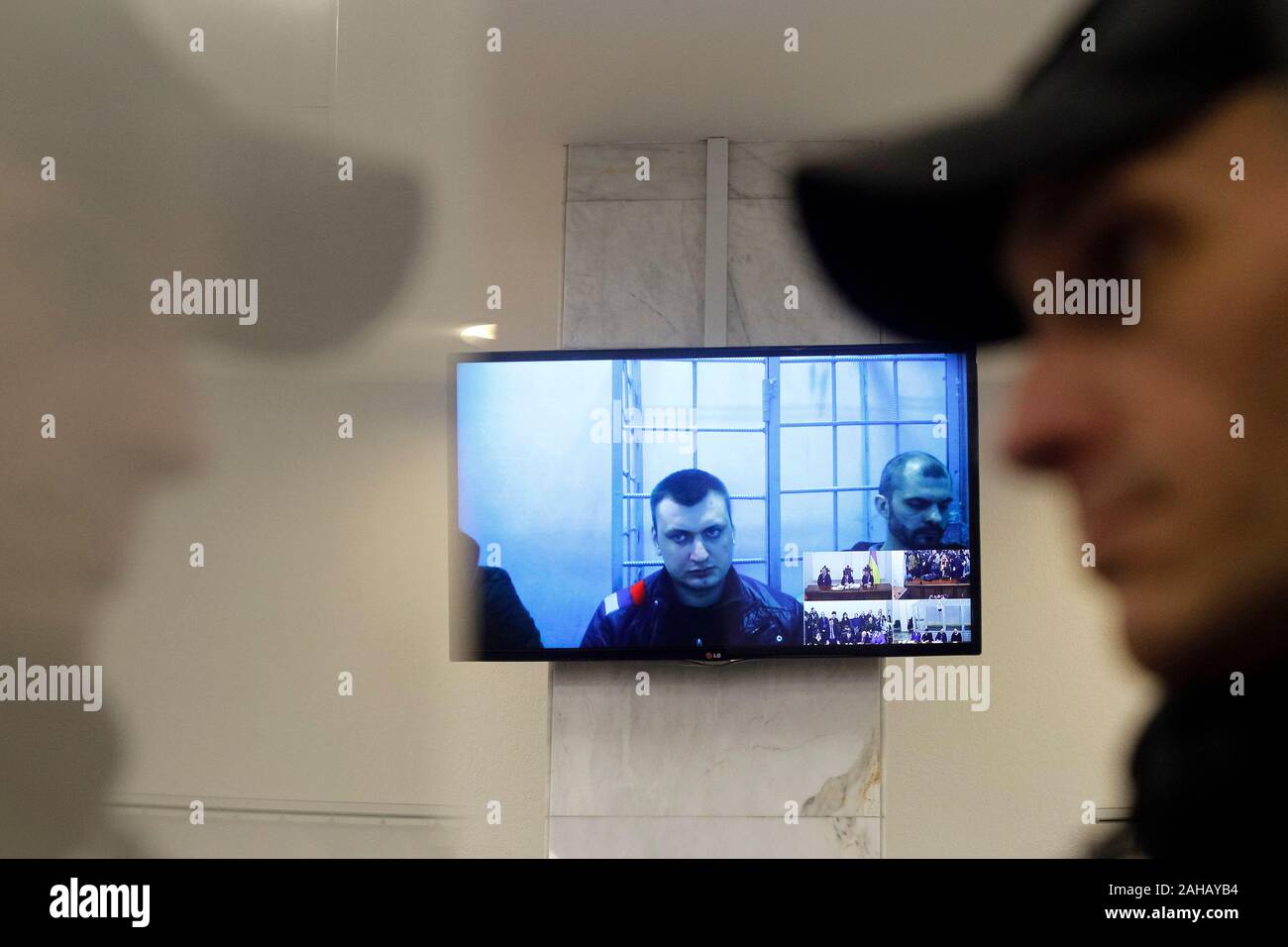 Serhii Zinchenko, Pavlo et Yanyshevsky Abroskin Oleh, anciens membres de la police anti-émeute Berkut, accusés de meurtre de manifestants au cours de l'Euromaidan manifestations en 2014, ont été observés sur un écran qu'ils y participent par liaison vidéo lors d'une audience à la Cour d'appel de Kiev. Banque D'Images