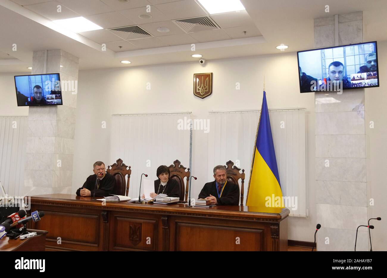 Serhii Zinchenko, Pavlo et Yanyshevsky Abroskin Oleh, anciens membres de la police anti-émeute Berkut, accusés de meurtre de manifestants au cours de l'Euromaidan manifestations en 2014, ont été observés sur un écran qu'ils y participent par liaison vidéo lors d'une audience à la Cour d'appel de Kiev. Banque D'Images