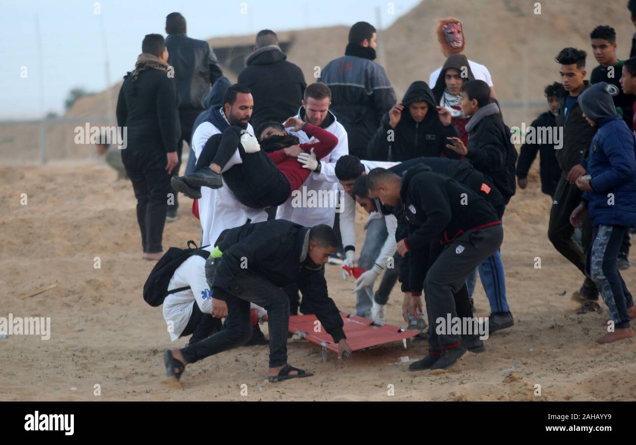 Rafah, Gaza. Dec 27, 2019. Emporter des Palestiniens un manifestant blessé lors de heurts après une manifestation le long de la frontière avec Israël à l'est de Rafah dans le sud de la bande de Gaza. le vendredi, Décembre 27, 2019. Les Palestiniens de Gaza, manifestations retour le long de la frontière fortifiée avec Israël, des factions dans la bande de Gaza, a déclaré jeudi, Photo par Ismael Mohamad/UPI UPI/Alamy Crédit : Live News Banque D'Images