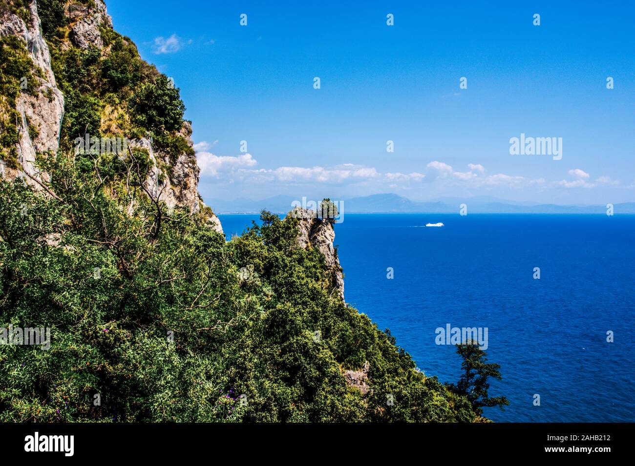 Vue panoramique sur la côte amalfitaine, rochers montagne falaise couverte d'arbres et de plantes sauvages, montagnes de la mer tyrrhénienne et ciel. Banque D'Images