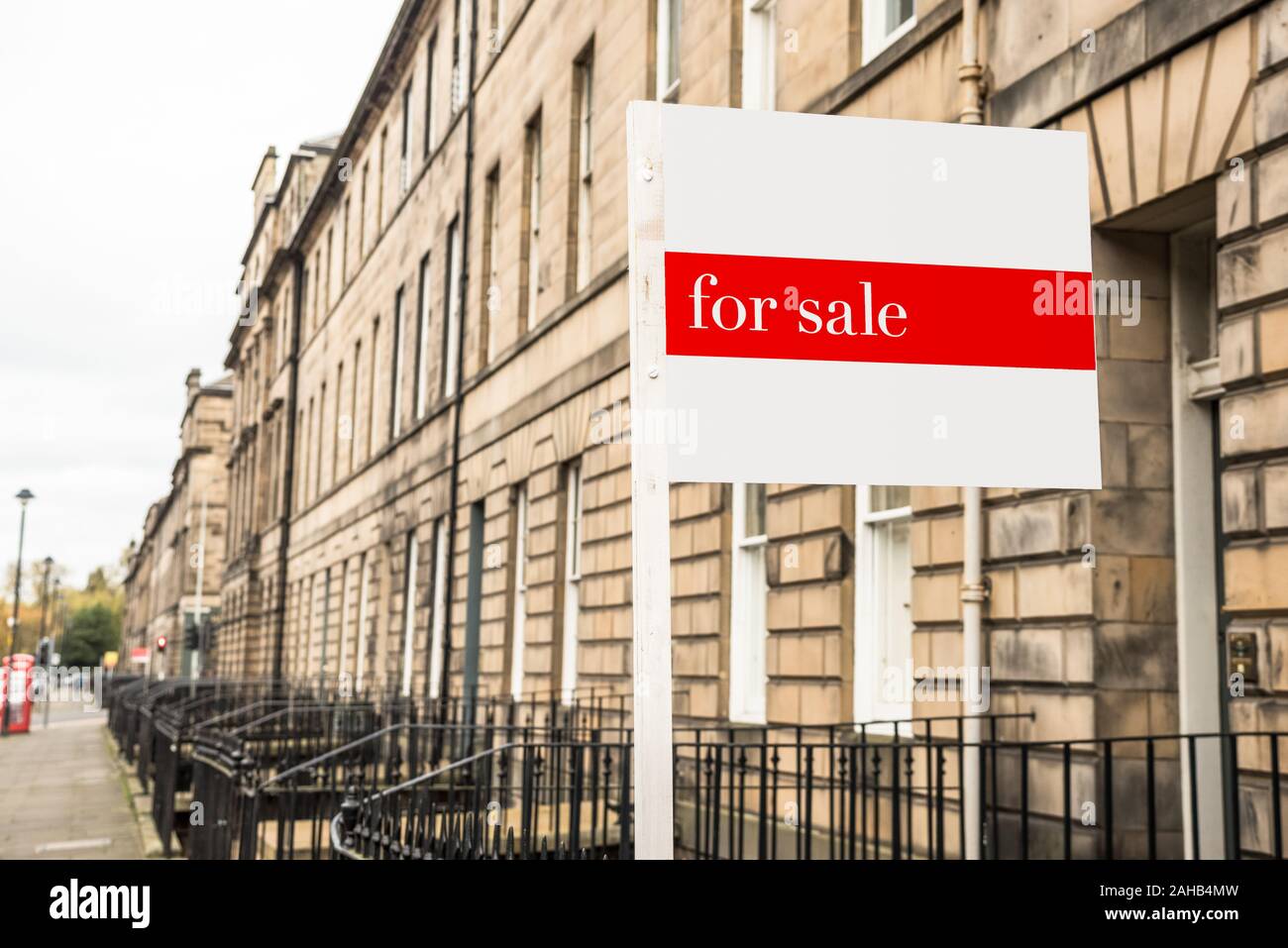 Rea estate signe devant une maison en pierre en vente dans un centre-ville sur un jour d'automne nuageux Banque D'Images