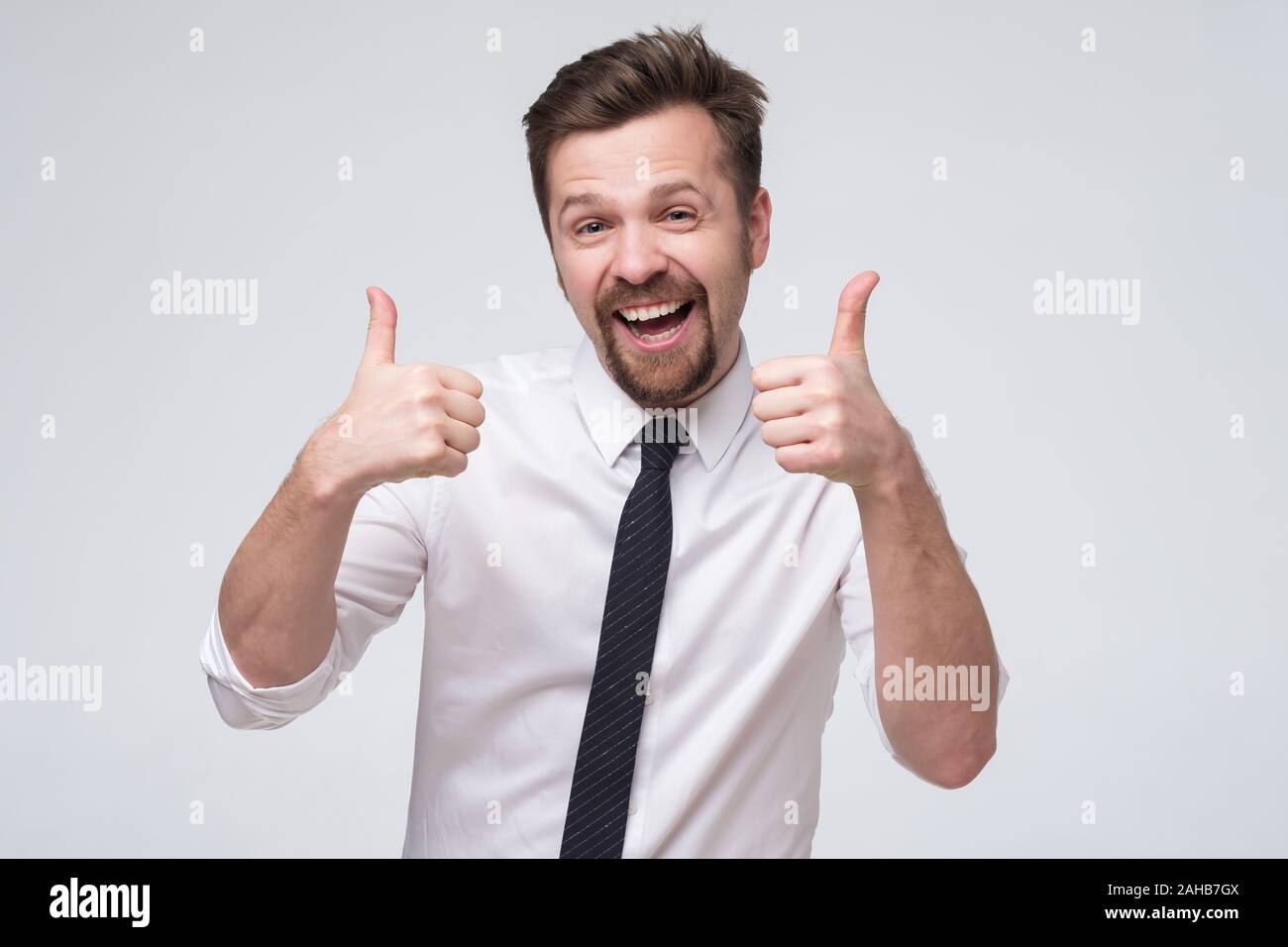 Happy young manager homme en cravate et chemise blanche avec geste Thumbs up Banque D'Images