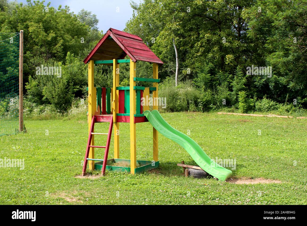 Vintage Retro extérieur en bois coloré jeu public matériel en forme de  toboggan en plastique entouré d'herbe et des arbres denses dans  l'appartement Photo Stock - Alamy