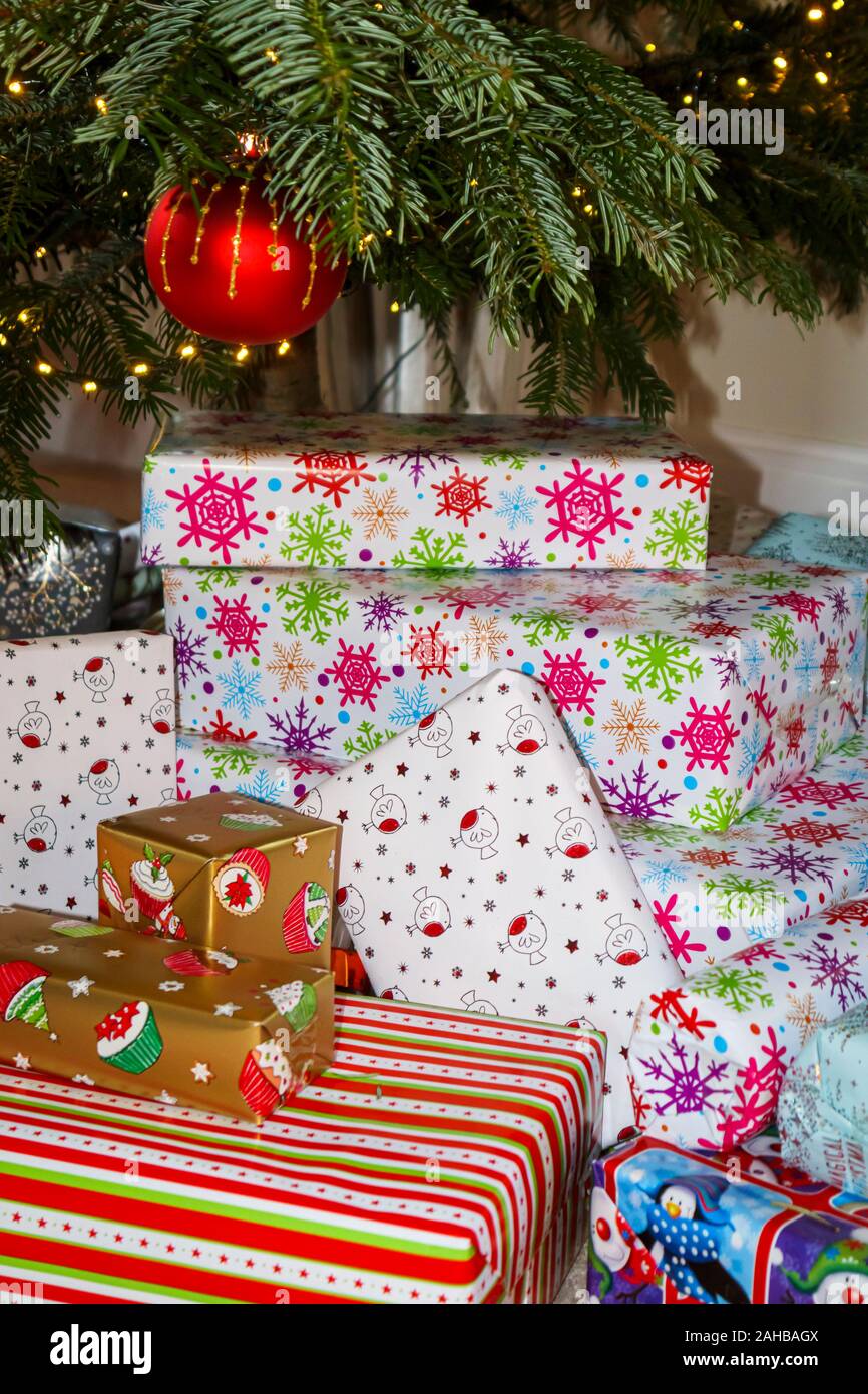 Pile de traditionnelle colorée typique de Noël ou des cadeaux emballés présente sous un arbre de Noël au Royaume-Uni des fêtes Banque D'Images