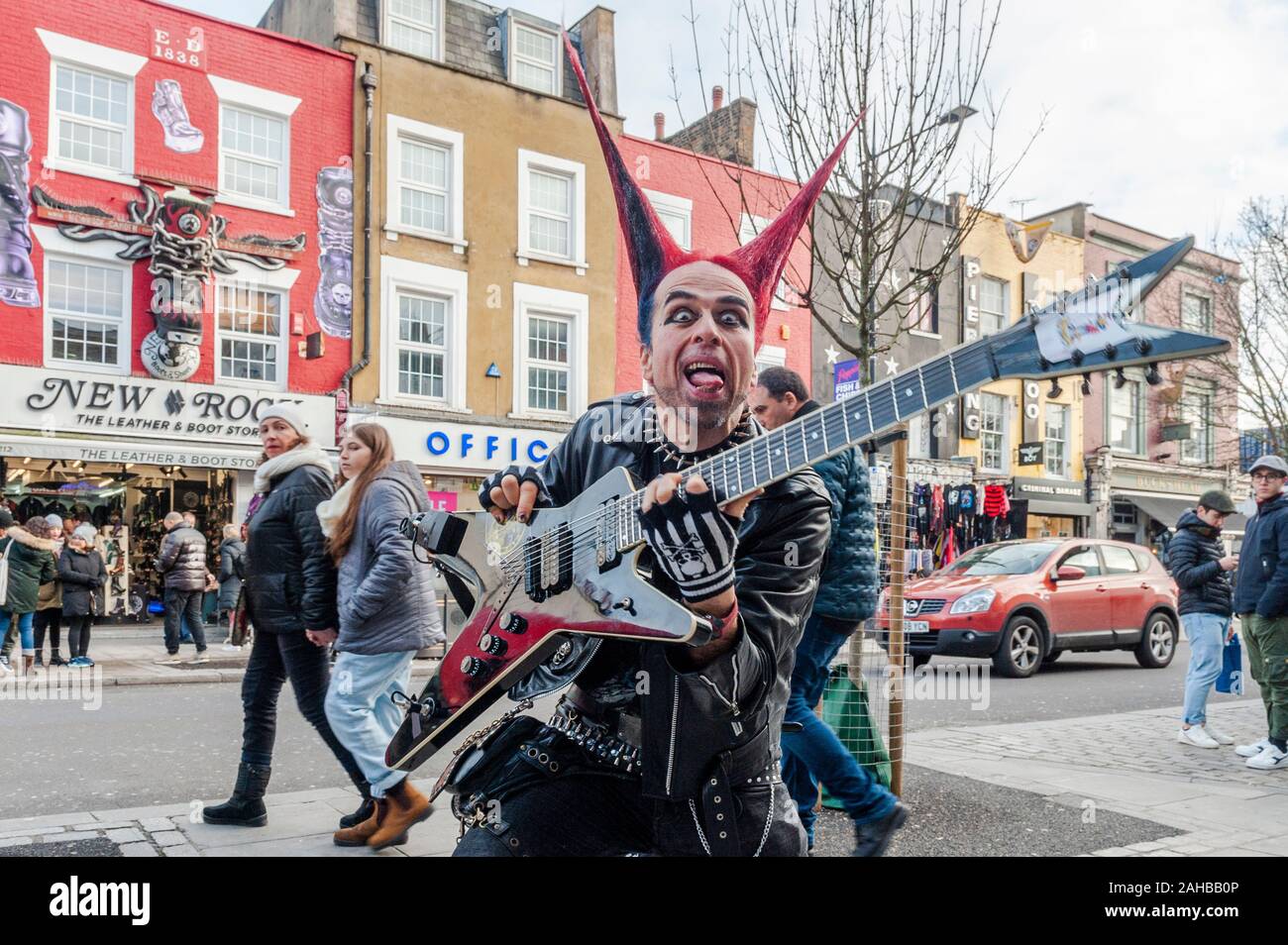 Homme vêtu de vêtements Punk Rocker avec des cheveux à pointes et une pose de guitare pour des images touristiques sur Camden High Street, Camden, Londres, Royaume-Uni. Banque D'Images