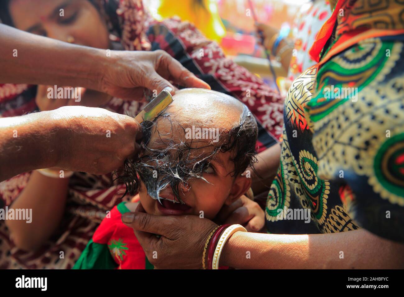 Mère et père regardant la coiffure de la tête de leur fille pendant la Bou Mela. Le Bangladesh Narayanganj Banque D'Images