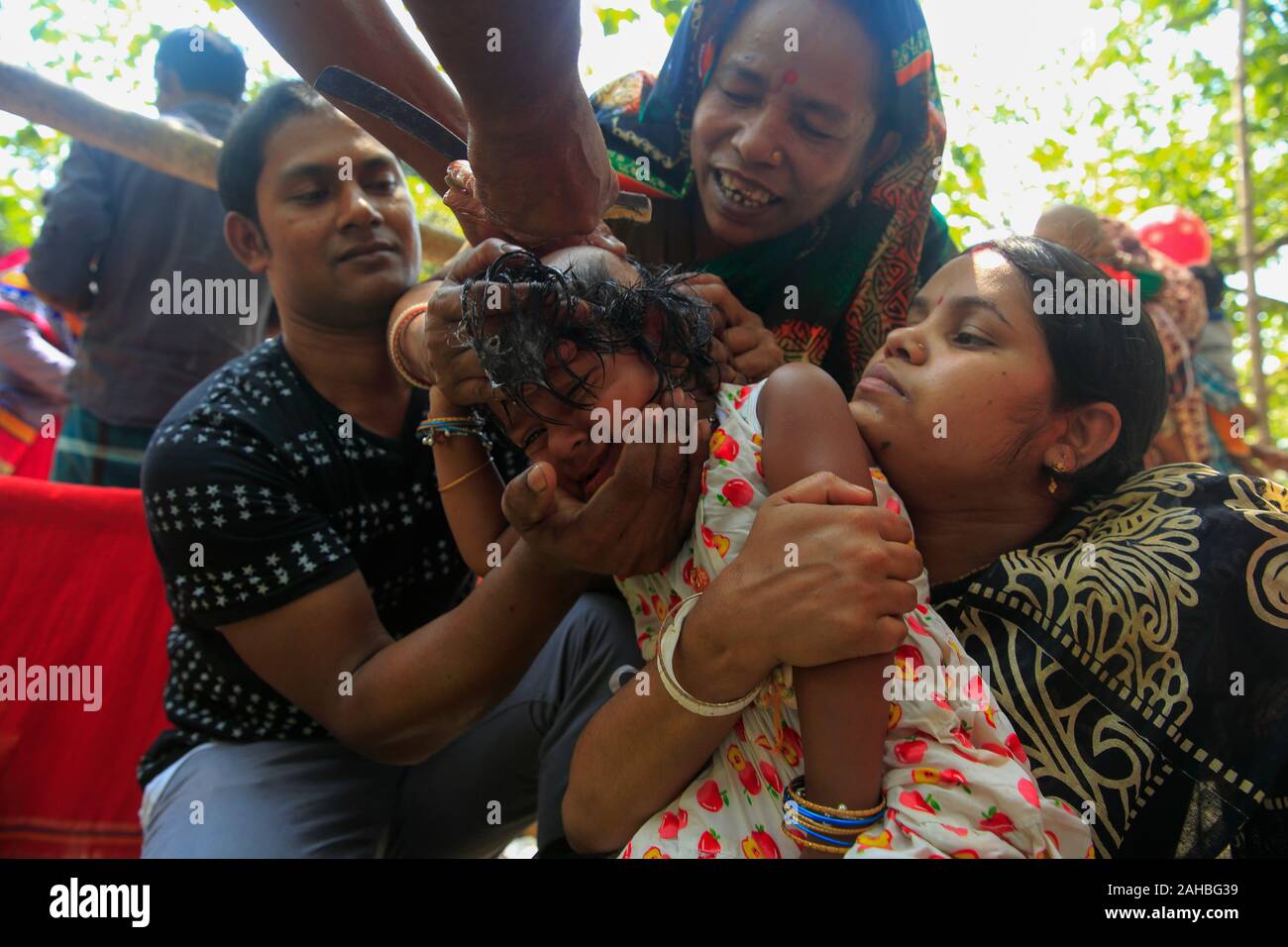 Mère et père regardant la coiffure de la tête de leur fille pendant la Bou Mela. Le Bangladesh Narayanganj Banque D'Images