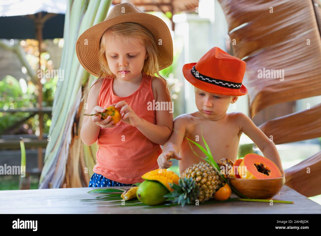 Drôle de photo frères. Couple d'enfants heureux avec visage souriant de manger les fruits tropicaux exotiques. L'alimentation saine, les pique-nique sur Luxury Resort. Banque D'Images
