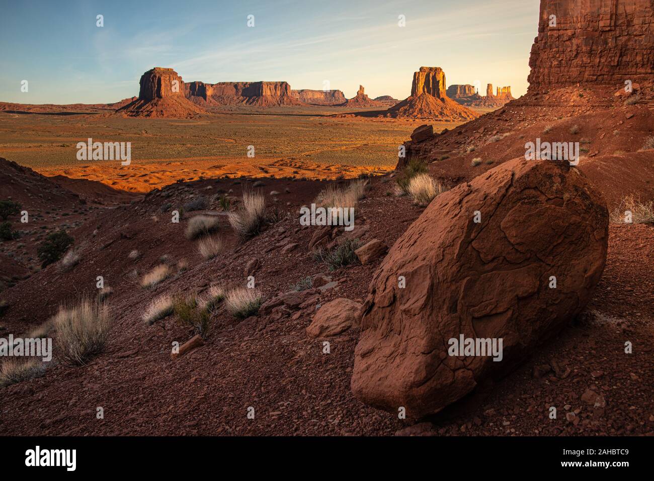Point de l'artiste, Monument Valley, AZ au lever du soleil. Le grand rocher rouge dans l'avant-plan sombre contraste l'East Mitten Butte en arrière-plan. Banque D'Images
