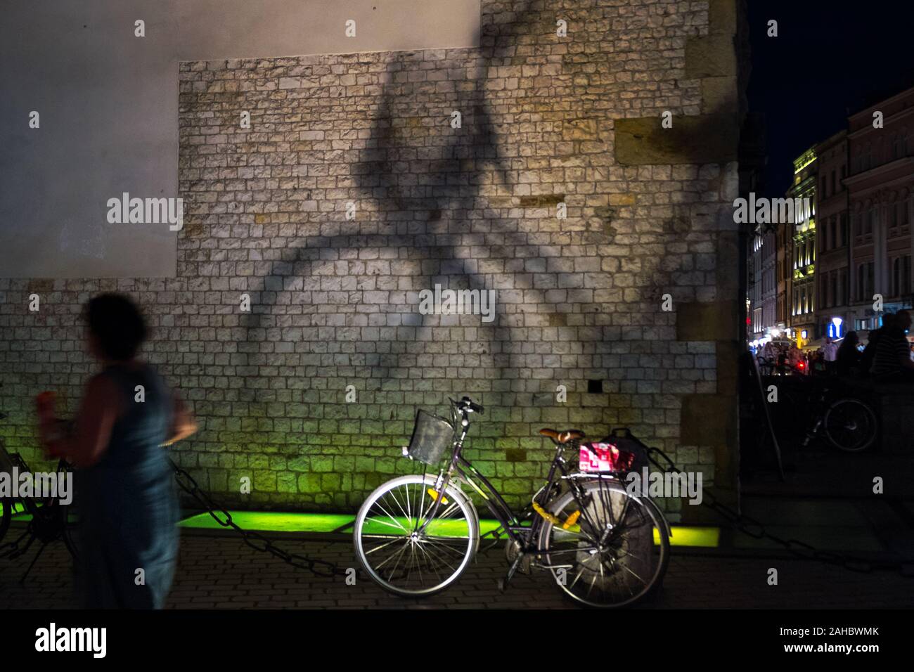 Ombre d'un vélo contre un mur éclairé de nuit, Kraków, Pologne Banque D'Images