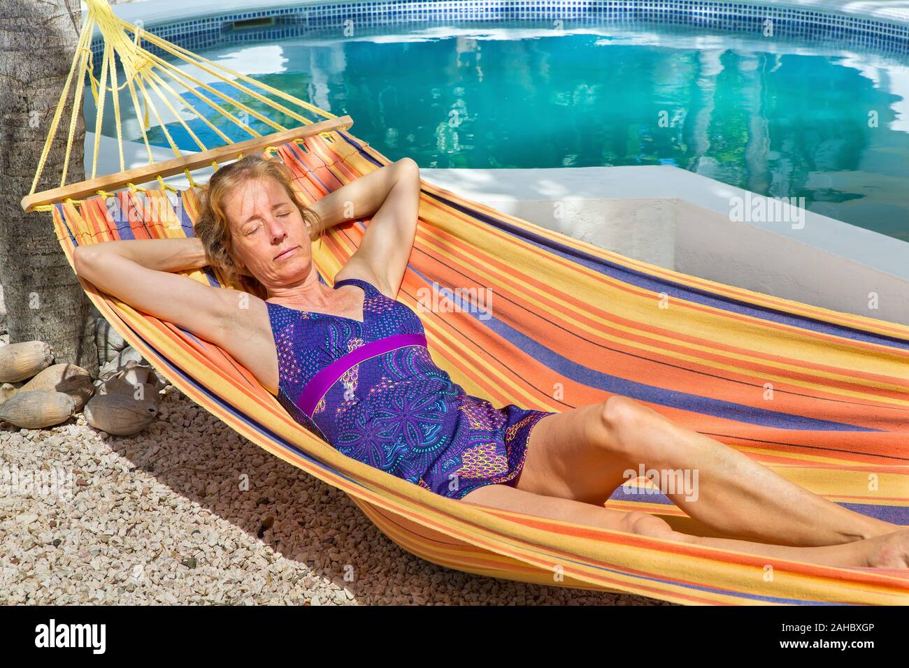 Femme couchée dans un hamac coloré près de bassin de baignade Banque D'Images