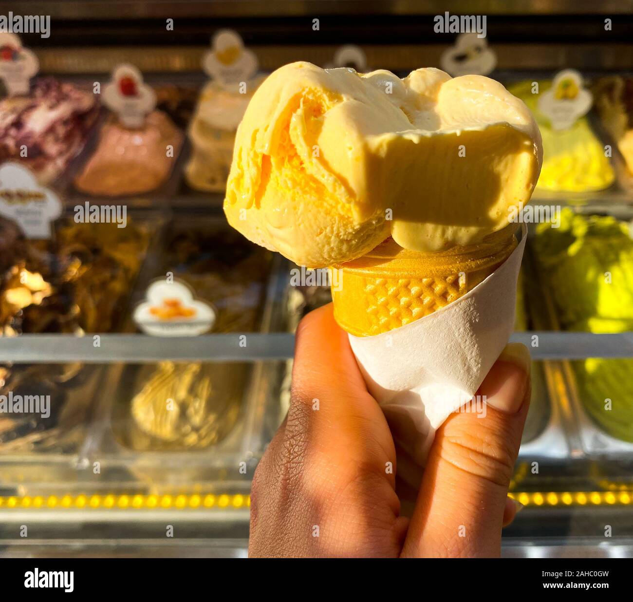 Main de femme, dans une glace jaune sur fond de compteur avec la crème glacée. Place pour le texte. Voyages. Banque D'Images