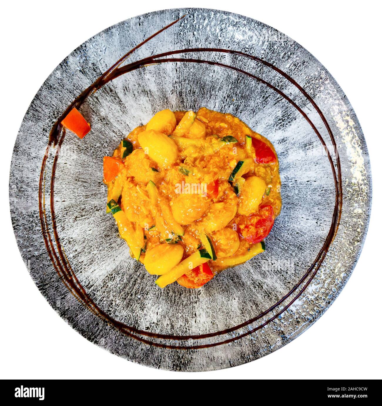 Vue de dessus du plat de céramique avec gnocchi italiens traditionnels avec les courgettes et le saumon dans la sauce aux légumes. Plus isolé sur fond blanc Banque D'Images