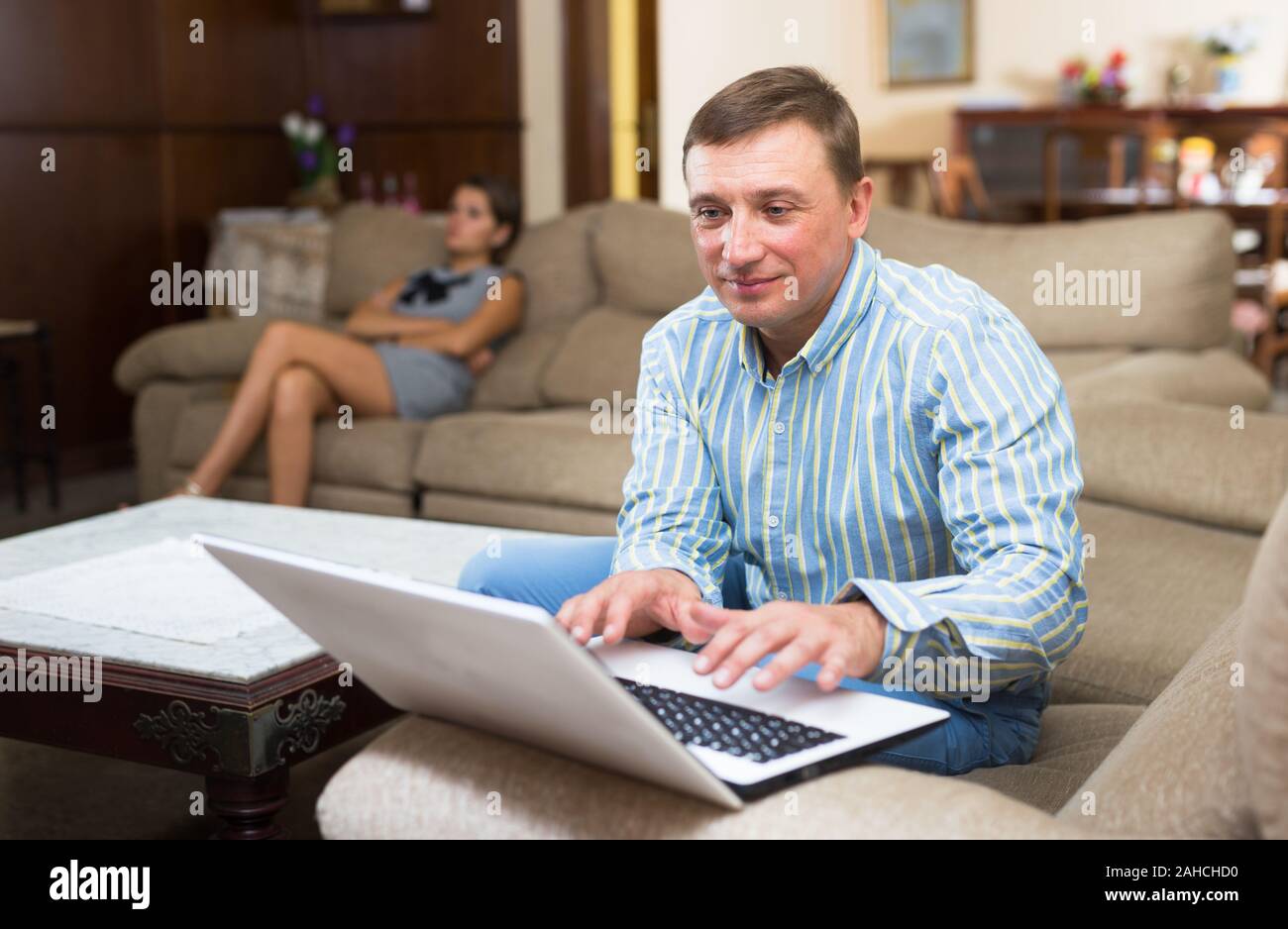 Femme assis offensé alors que son mari à l'aide d'ordinateur portable à la maison Banque D'Images