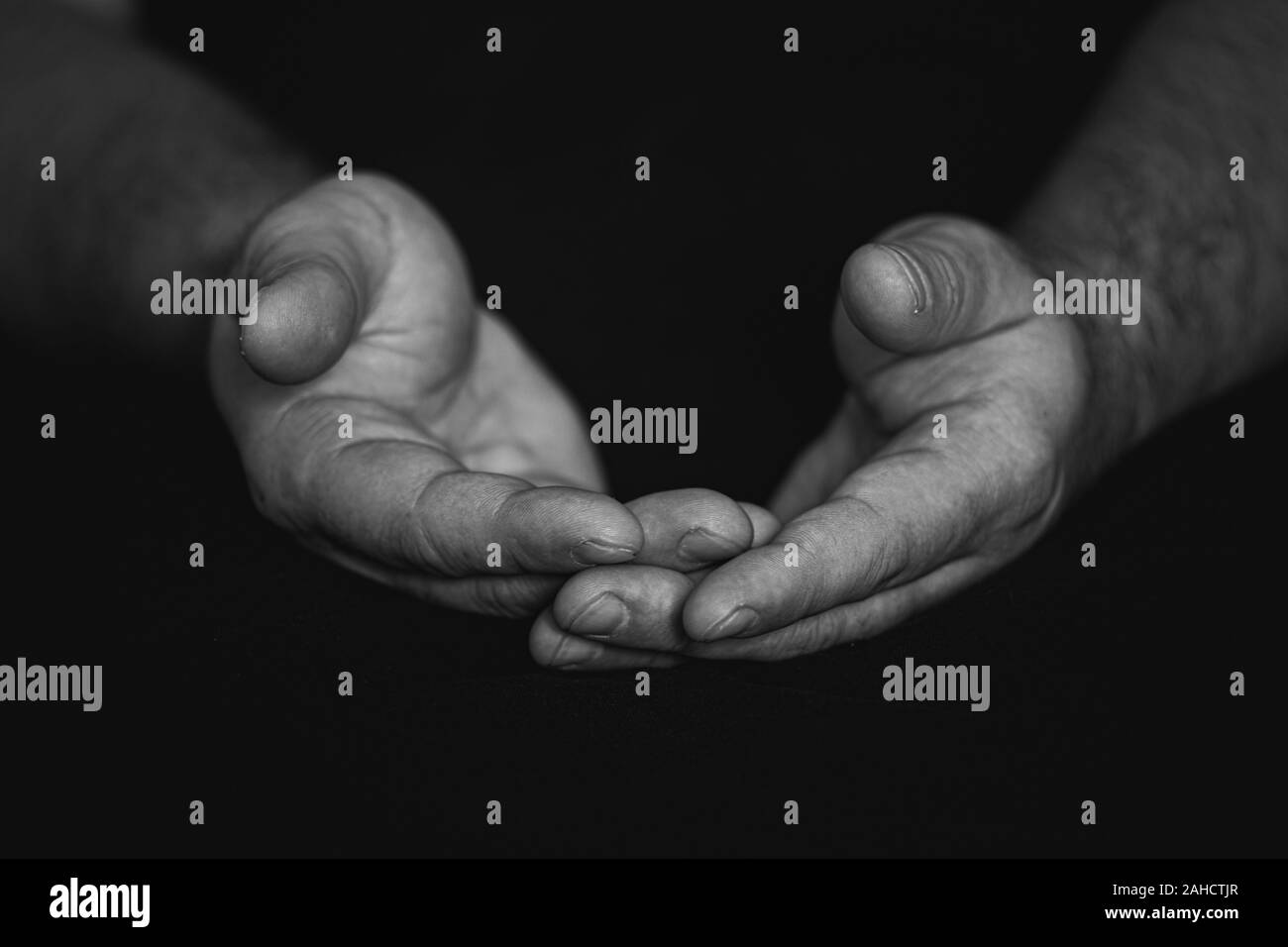 Touche bas, près des mains d'un homme mûr fidèles priant, les mains croisées, les doigts entrelacés dans le culte à Dieu. Fond noir isolé. Concept Banque D'Images