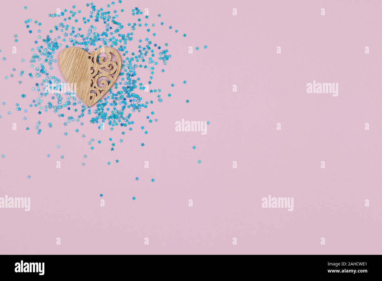 Coeur en bois avec des motifs sur fond rose avec des étoiles bleues haut voir télévision jeter copy space Banque D'Images Coeur en bois avec des motifs sur fond rose avec des étoiles bleues haut voir télévision jeter copy space Banque D'Images