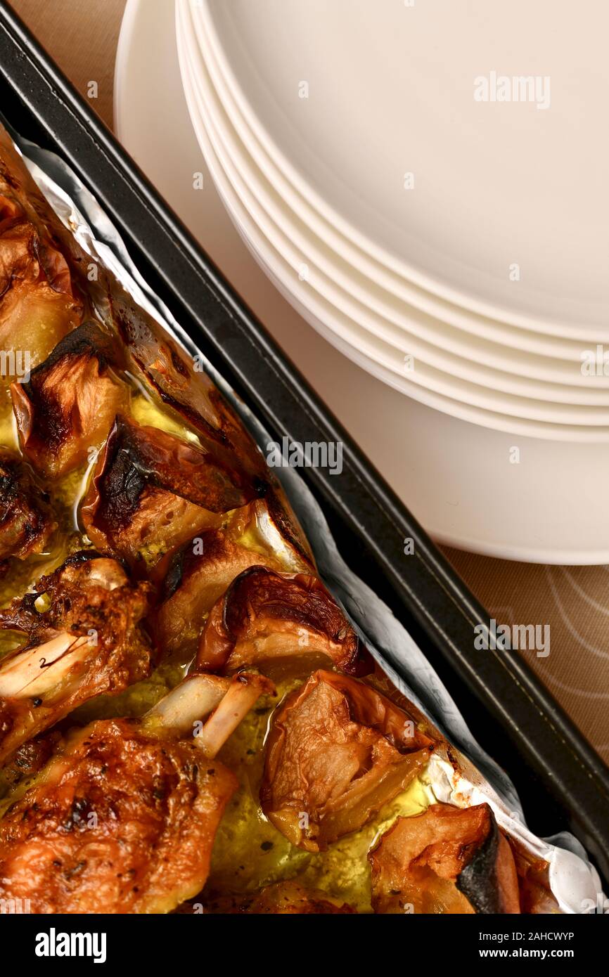 Les plaques d'une pile dans l'angle supérieur droit et une casserole avec fried turquie ailes avec les pommes, coin inférieur gauche, à la verticale. Banque D'Images