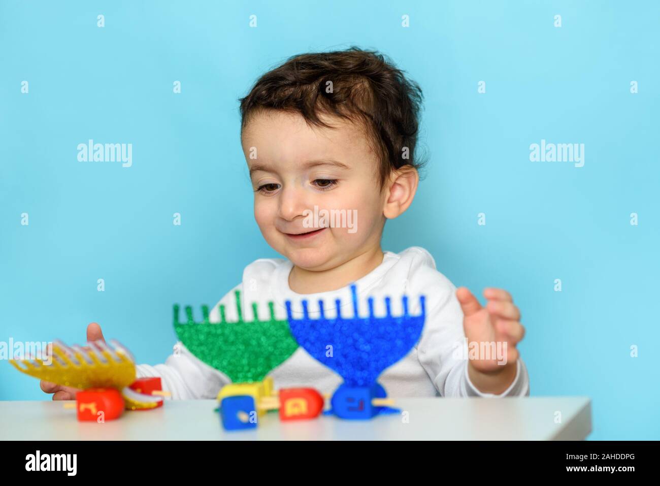 Garçon juif jouer avec Festive Hanouka Hanouka Fête Menorah bleu et vert et bois colorés Dreidels. Selective Focus sur l'enfant. Banque D'Images