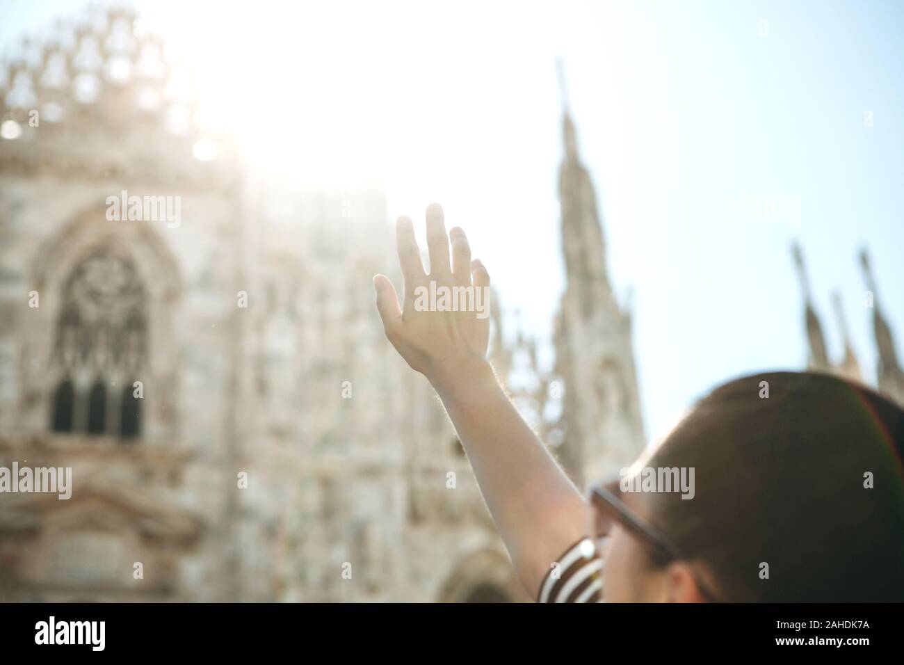 La jeune fille leva sa main à la lumière du soleil et la cathédrale Duomo de Milan en Italie. Banque D'Images