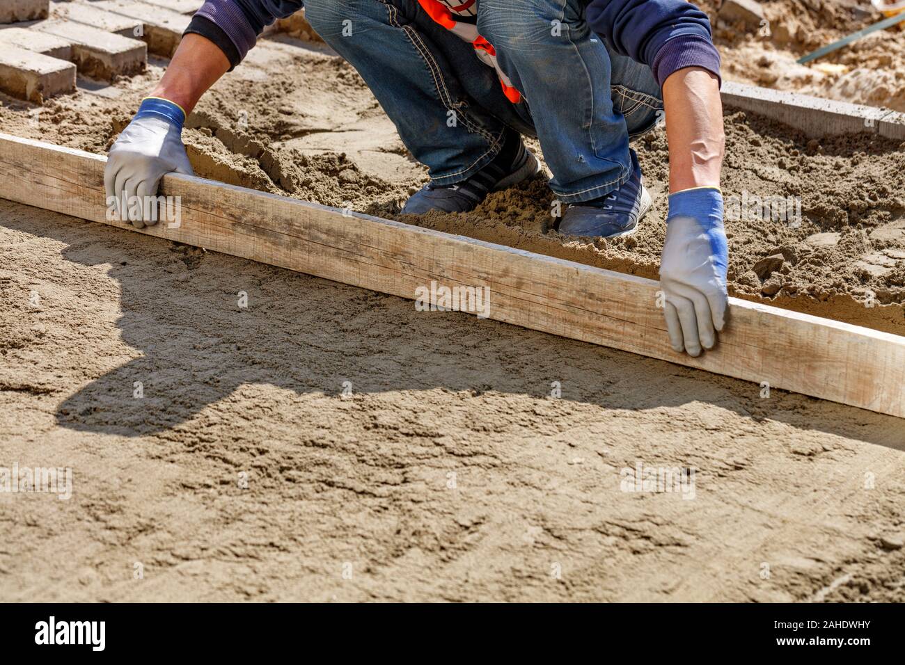 Les niveaux d'un travailleur la fondation de sable avec un niveau en bois pour continuer la pose des dalles, image avec copie espace libre, avec l'exemplaire de l'espace. Banque D'Images
