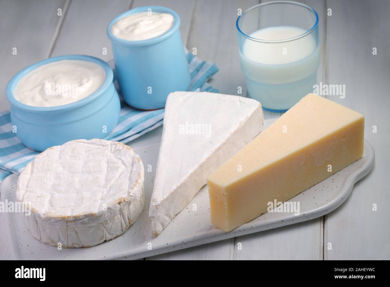 Produits laitiers : tree - types de fromage brie, camembert, et le Parmesan, une tasse de lait et deux pots de yaourt sur une table rustique Banque D'Images