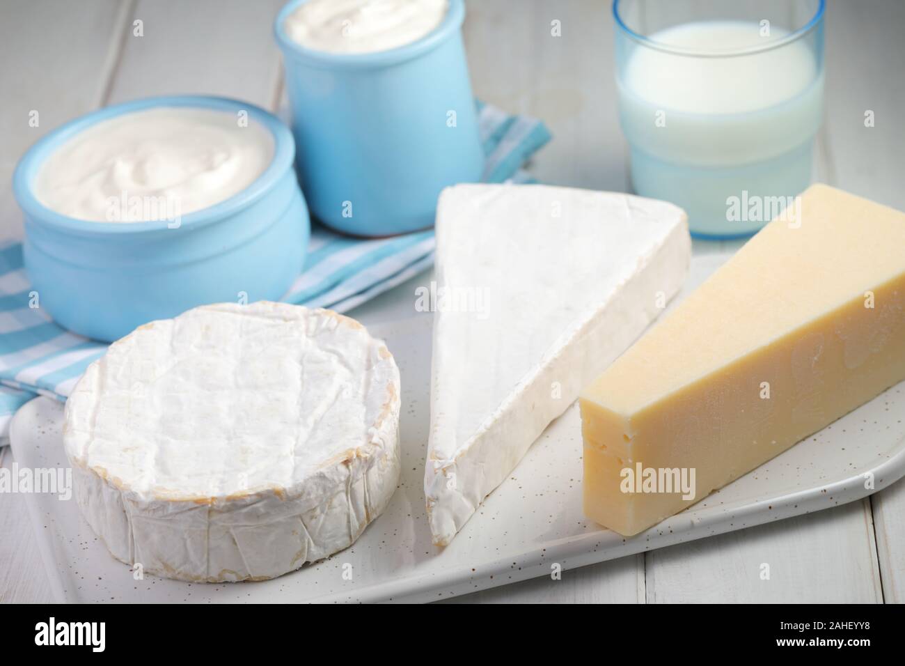 Produits laitiers : tree - types de fromage brie, camembert, et le Parmesan, une tasse de lait et deux pots de yaourt sur une table rustique Banque D'Images