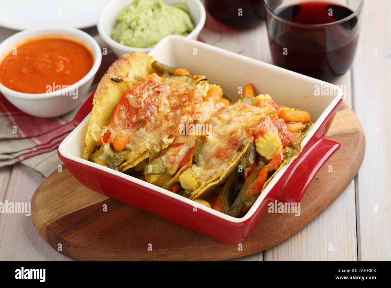 Tacos végétarien avec du fromage, de la guacamole, salsa, et de vin rouge sur une table rustique Banque D'Images