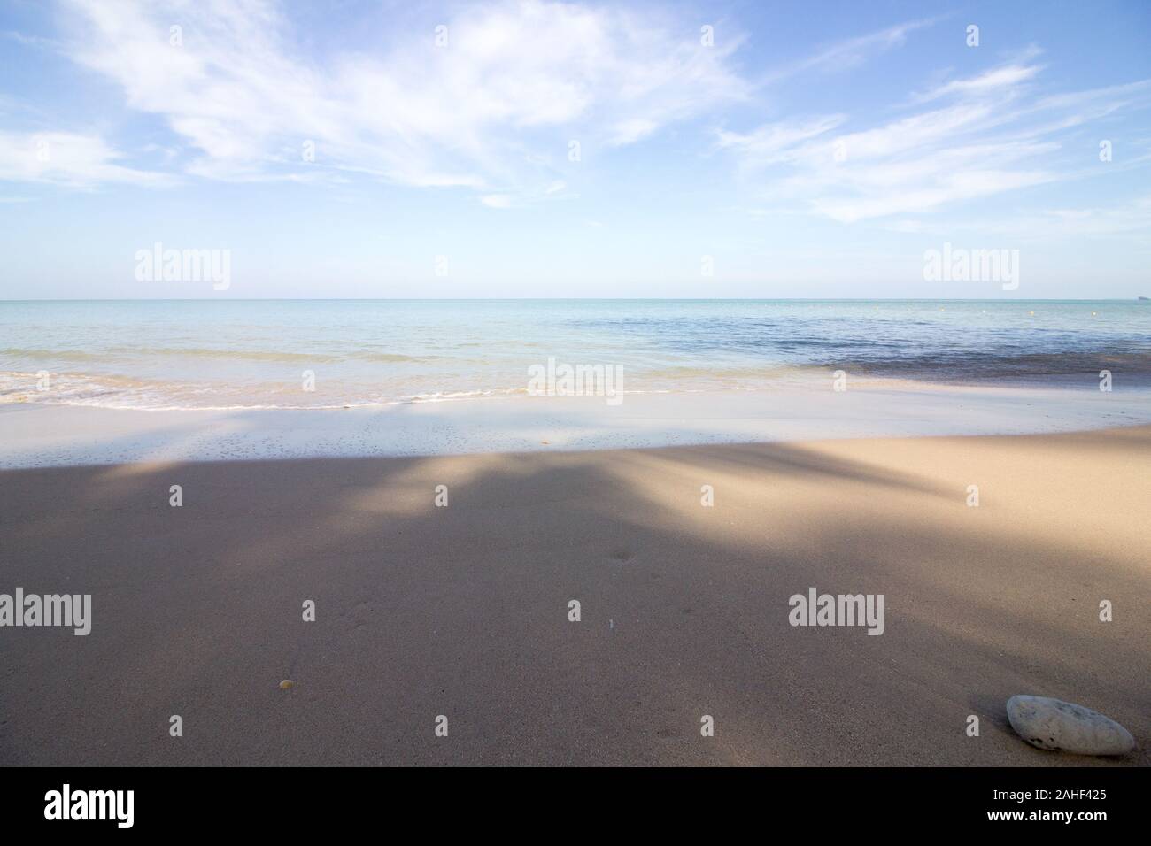 La mer calme sur une magnifique plage de sable s'écoule dans le ciel ensoleillé lumineux Banque D'Images