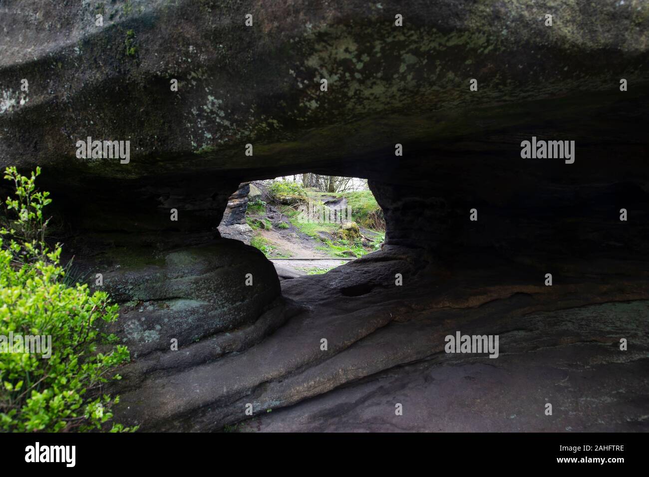 Voir à travers un trou formé naturellement dans une roche dues aux intempéries, de glace et de vent à Brimham Rocks, North Yorkshire, Angleterre Royaume-uni Banque D'Images