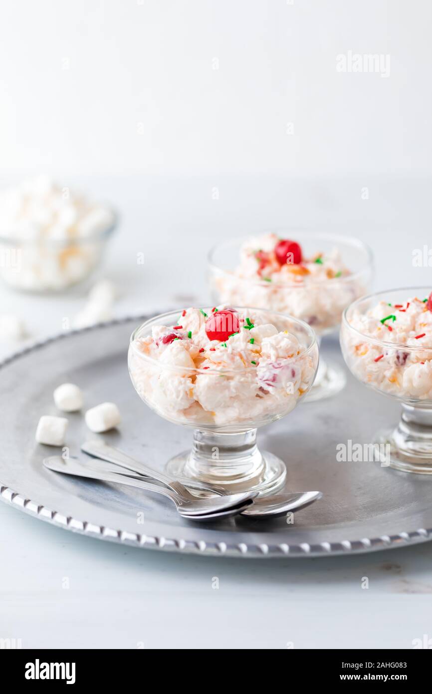 Une vue en gros de plats de salade Ambrosia sur un plateau de service en métal avec un petit bol de guimauves miniatures en derrière. Banque D'Images