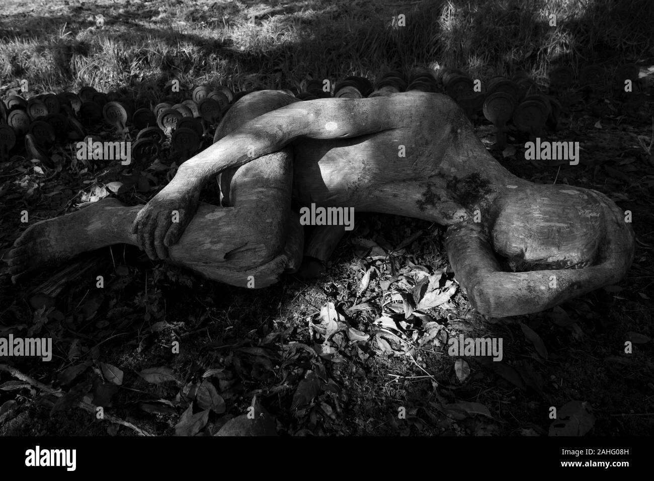 Une photo en noir et blanc d'un arbre tombé sculpture figure, en face de stèles funéraires. Par Peter Bolton. Cimetière de l'hôpital de Mendip dans Wells, Somerset. Banque D'Images