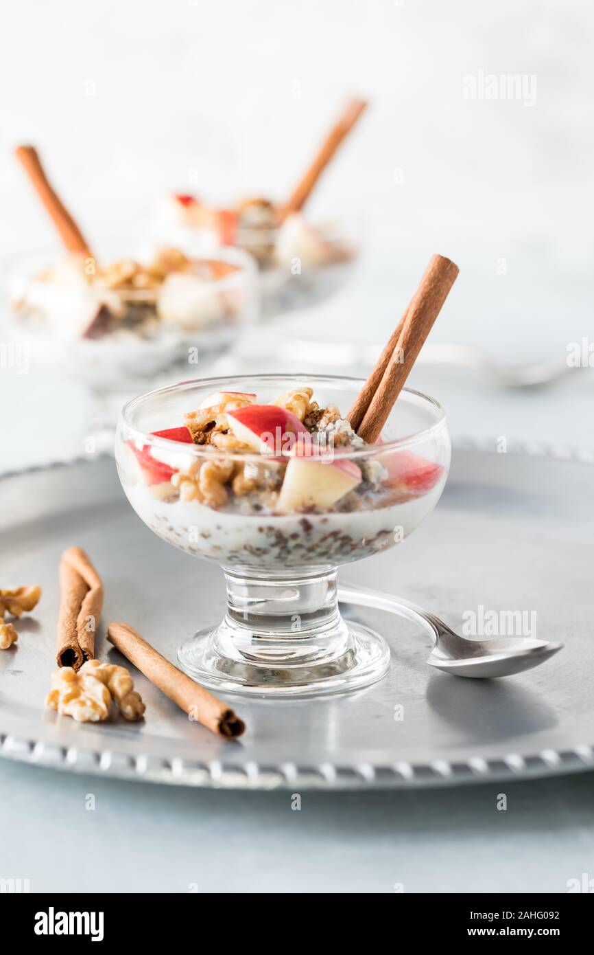 Une vue en gros plan d'un récipient en verre rempli d'avoine cuits coupés en acier combiné avec chia semences et graines de chanvre, et le sommet, avec des morceaux de pommes, noix et Banque D'Images