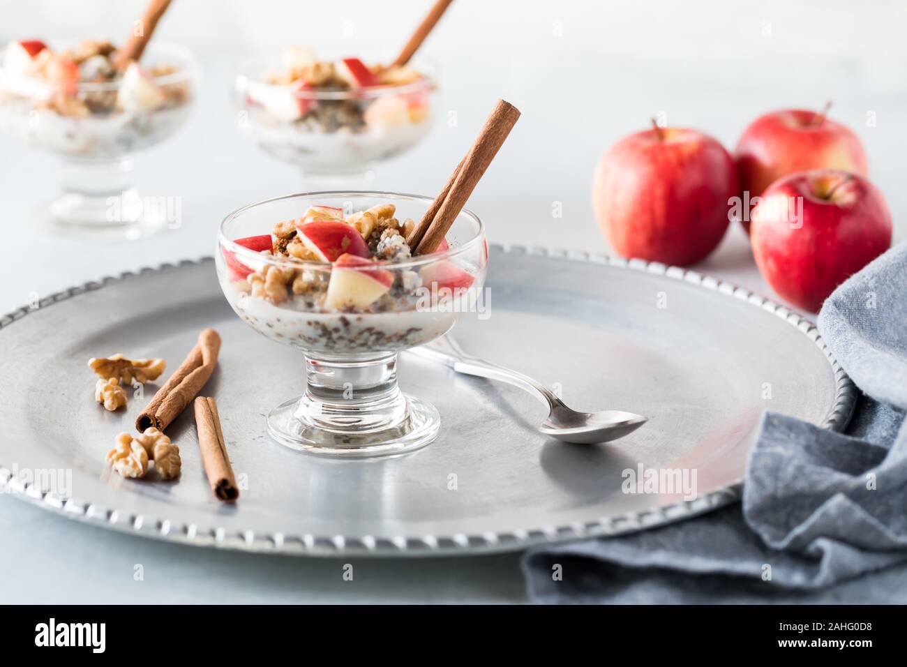 Un gros plan de coupe en acier plat en verre avec de l'avoine, les graines de chanvre et les graines de chia et garni avec des morceaux de pommes, les noix et la cannelle. Banque D'Images