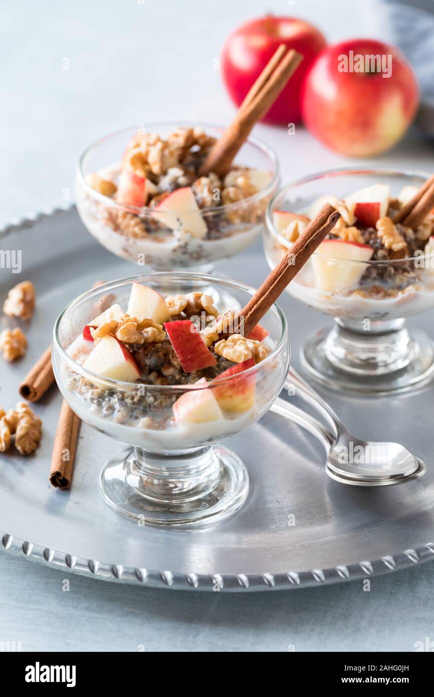 Une vue rapprochée de trois coupes en verre rempli d'avoine cuits coupés en acier et recouverte avec des morceaux de pommes, les noix et la cannelle. Banque D'Images