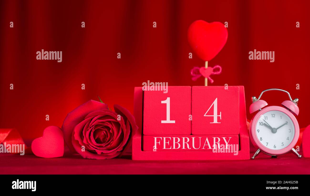 14 février le lettrage sur red cube de bois calendrier. Concept de la Saint-Valentin en face de tissu rouge arrière-plan. Banque D'Images