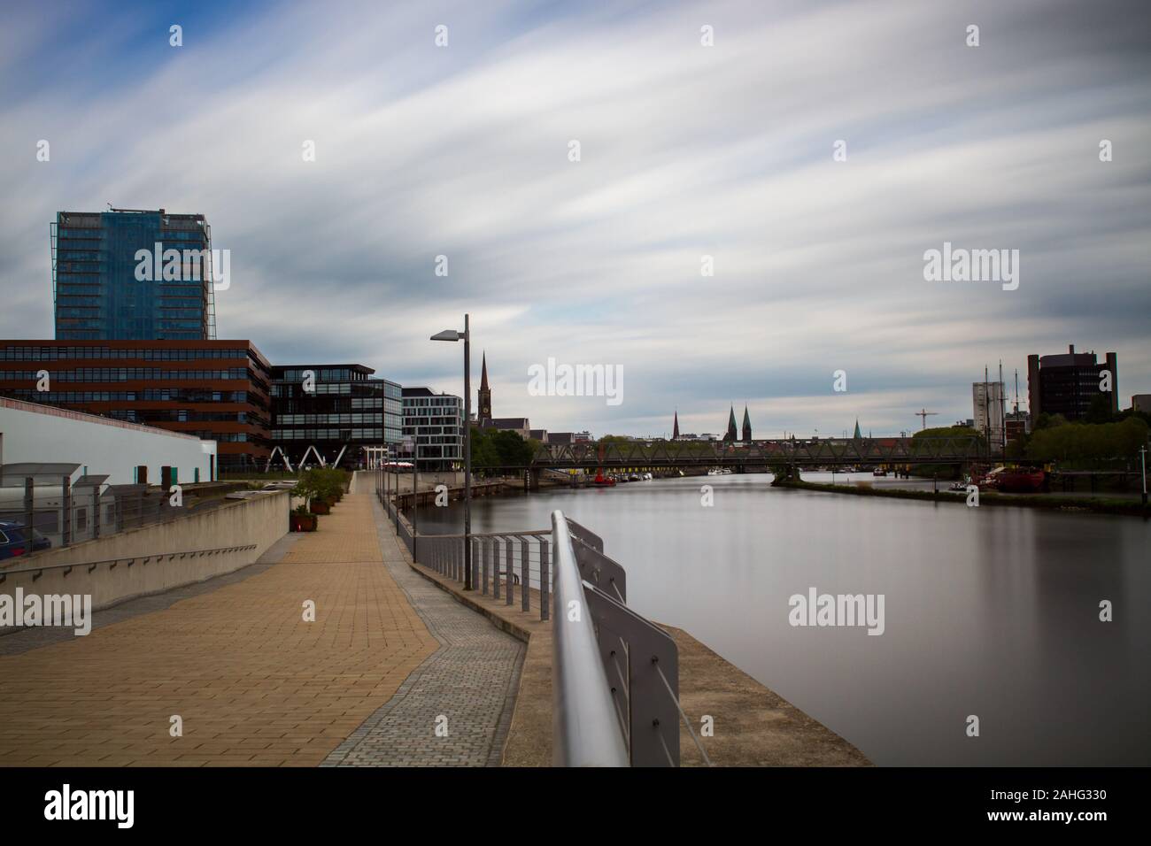 Une longue exposition de la Überseestadt à Brême, en Allemagne avec les immeubles de bureaux et ciel nuageux et la rivière Weser, dans l'avant-plan Banque D'Images
