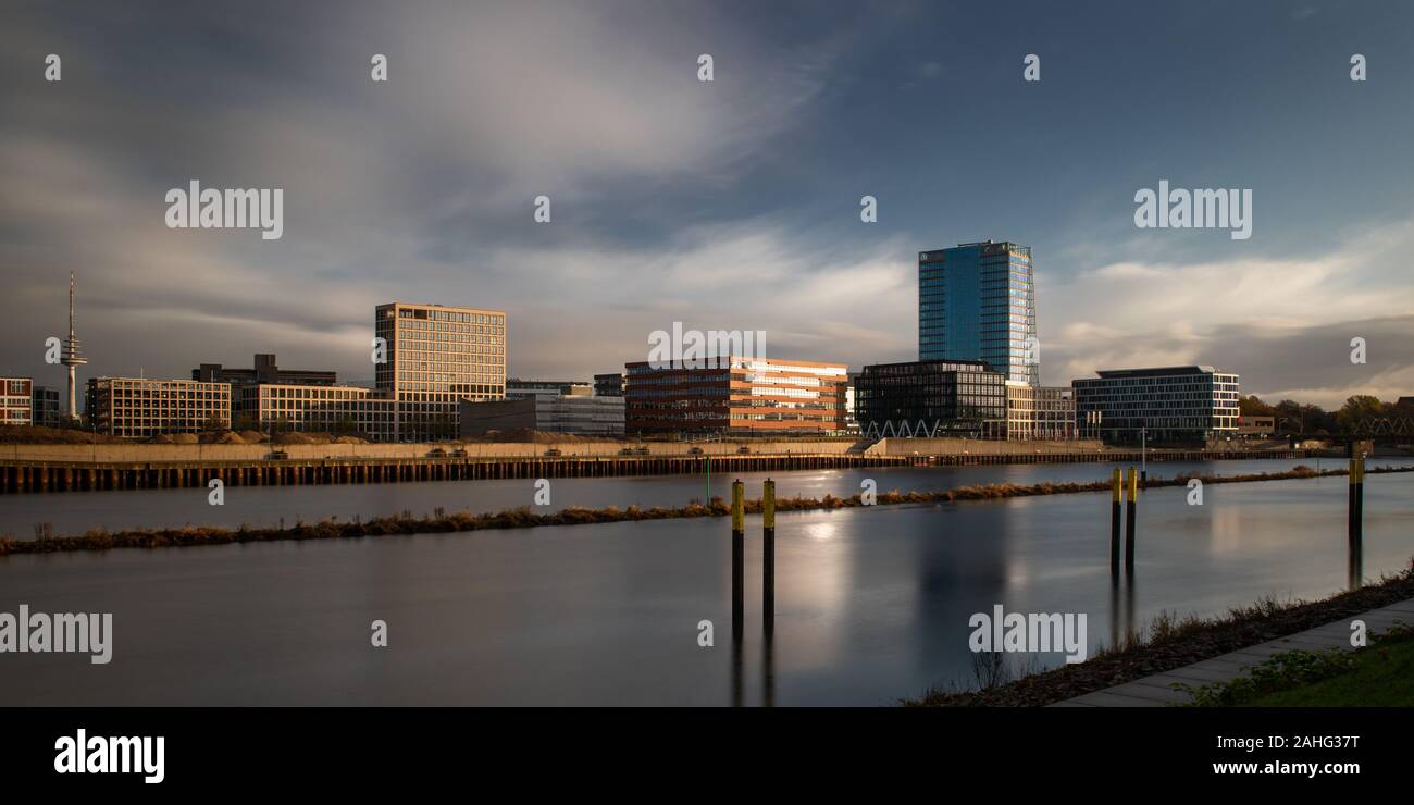 Une longue exposition de la Überseestadt à Brême, en Allemagne avec les immeubles de bureaux et ciel nuageux au lever du soleil Banque D'Images