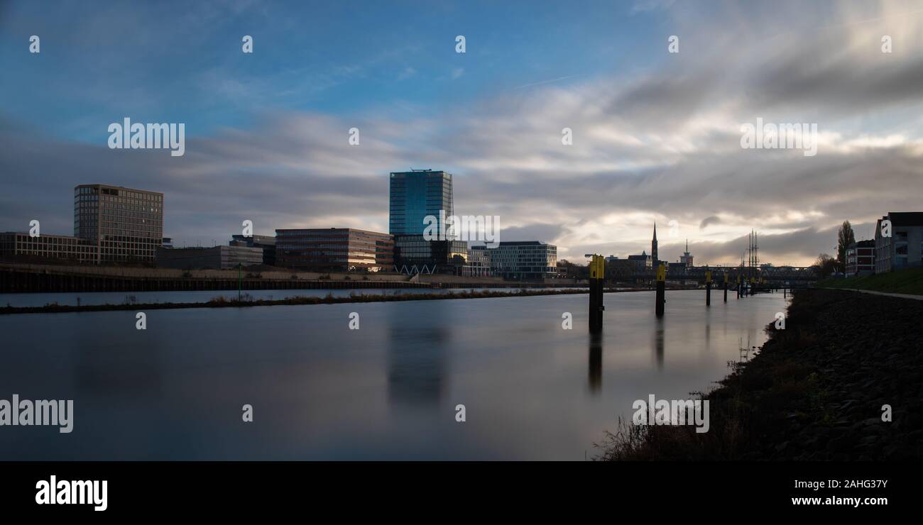 Une longue exposition de la Überseestadt à Brême, en Allemagne avec les immeubles de bureaux et ciel nuageux au lever du soleil Banque D'Images
