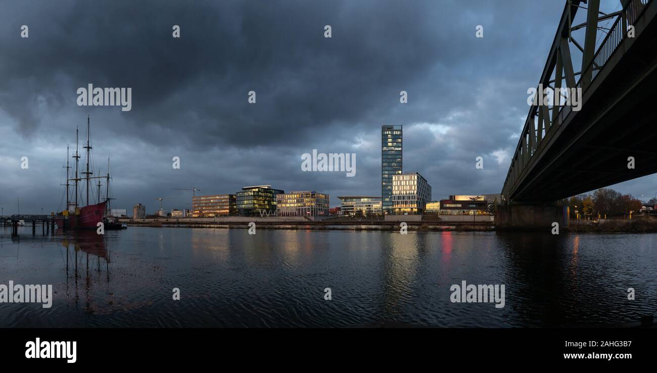 Überseestadt à Brême, en Allemagne, avec des réflexions sur la rivière Weser et lumières dans les immeubles de bureaux au cours de houer avec bleu ciel nuageux Banque D'Images