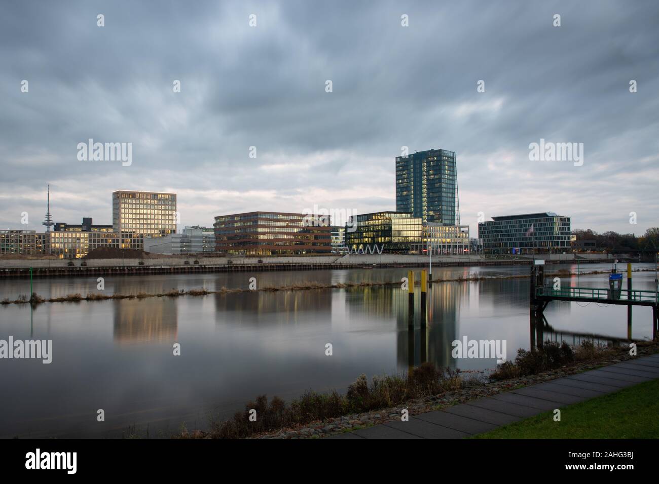 Überseestadt à Brême, en Allemagne, avec des réflexions sur la rivière Weser et lumières dans les immeubles de bureaux au cours de houer avec bleu ciel nuageux Banque D'Images