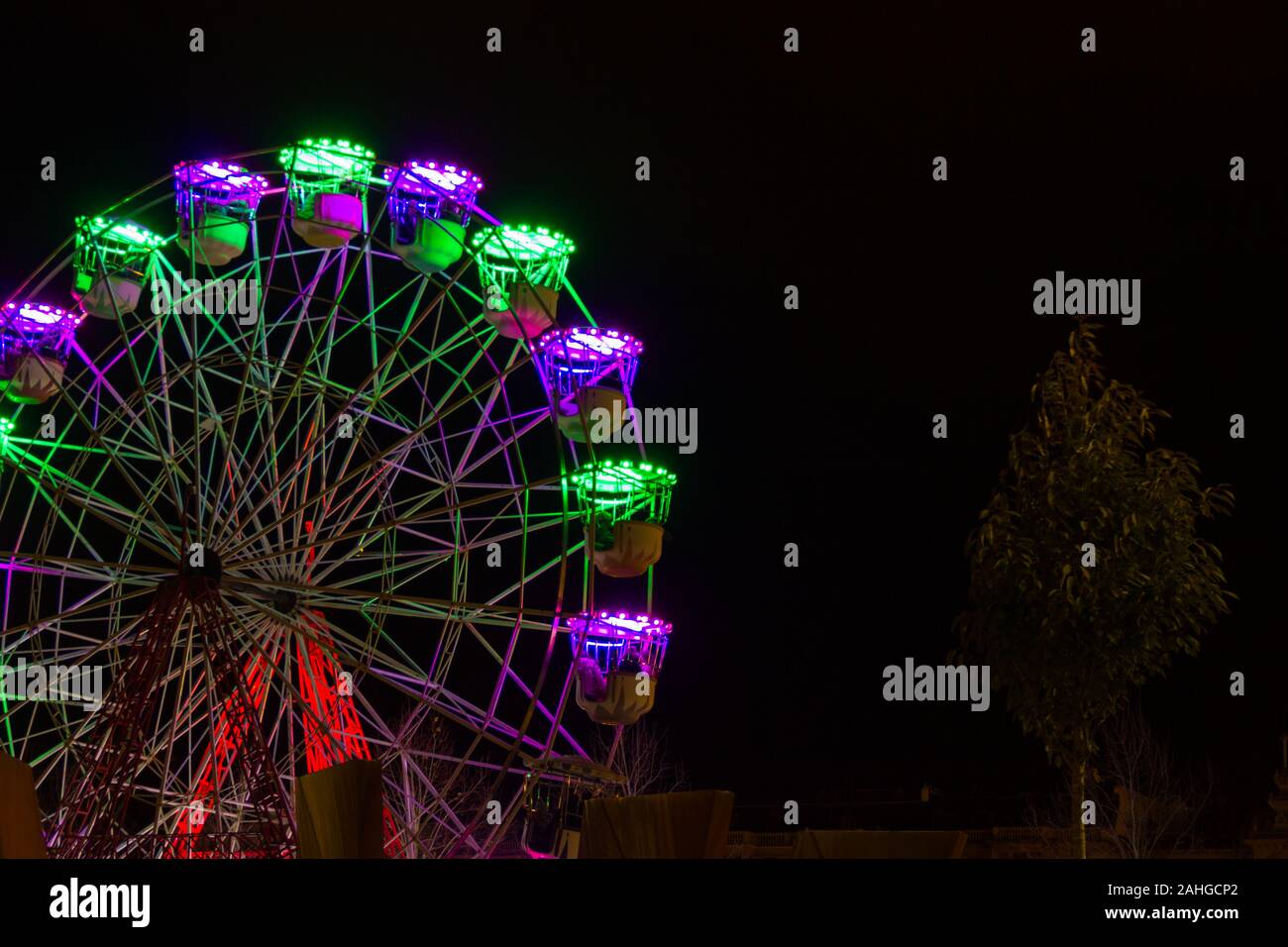 Grande roue avec des lumières fluo colorées en hiver Noël nuit à San Sebastian, Pays basque. Concept d'attraction amusante en plein air Banque D'Images